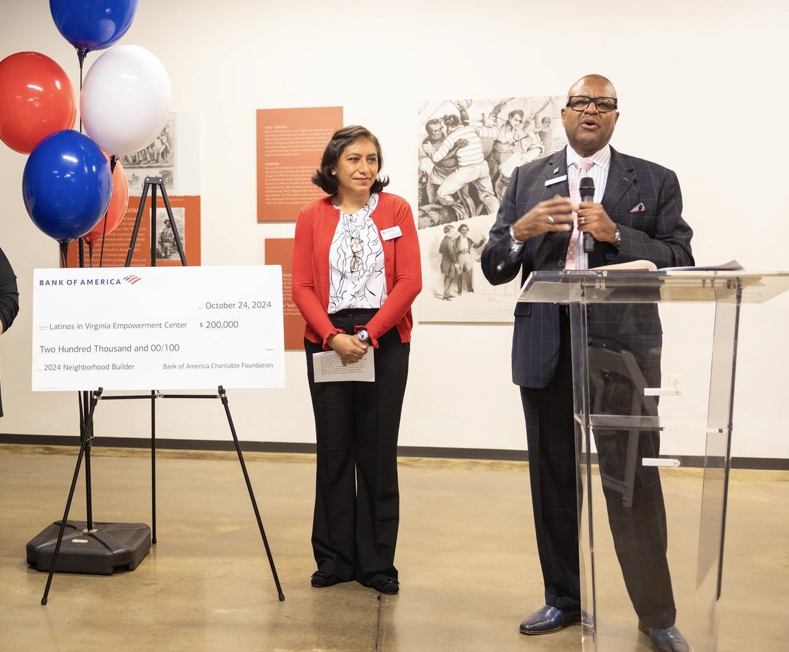 Un cheque de inversión comunitaria de Bank of America junto a Elvira y el orador del evento